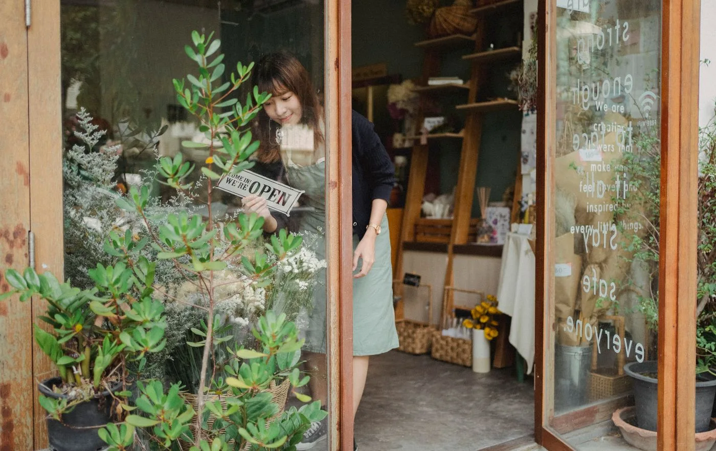 A florist adjusting a shop sign