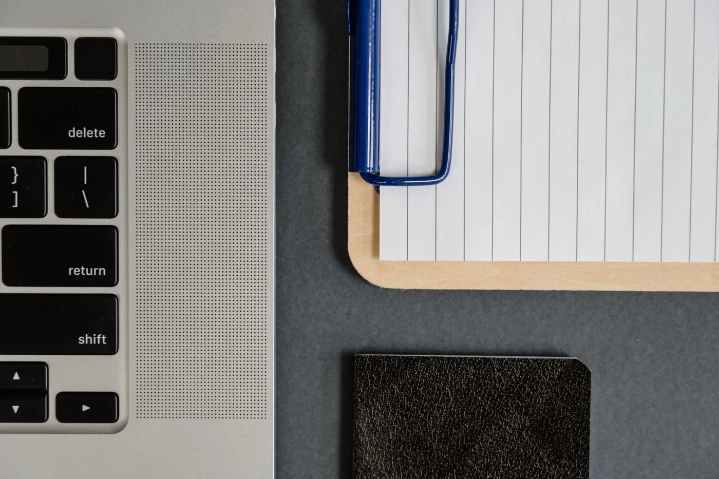 A clipboard and notebook beside a laptop