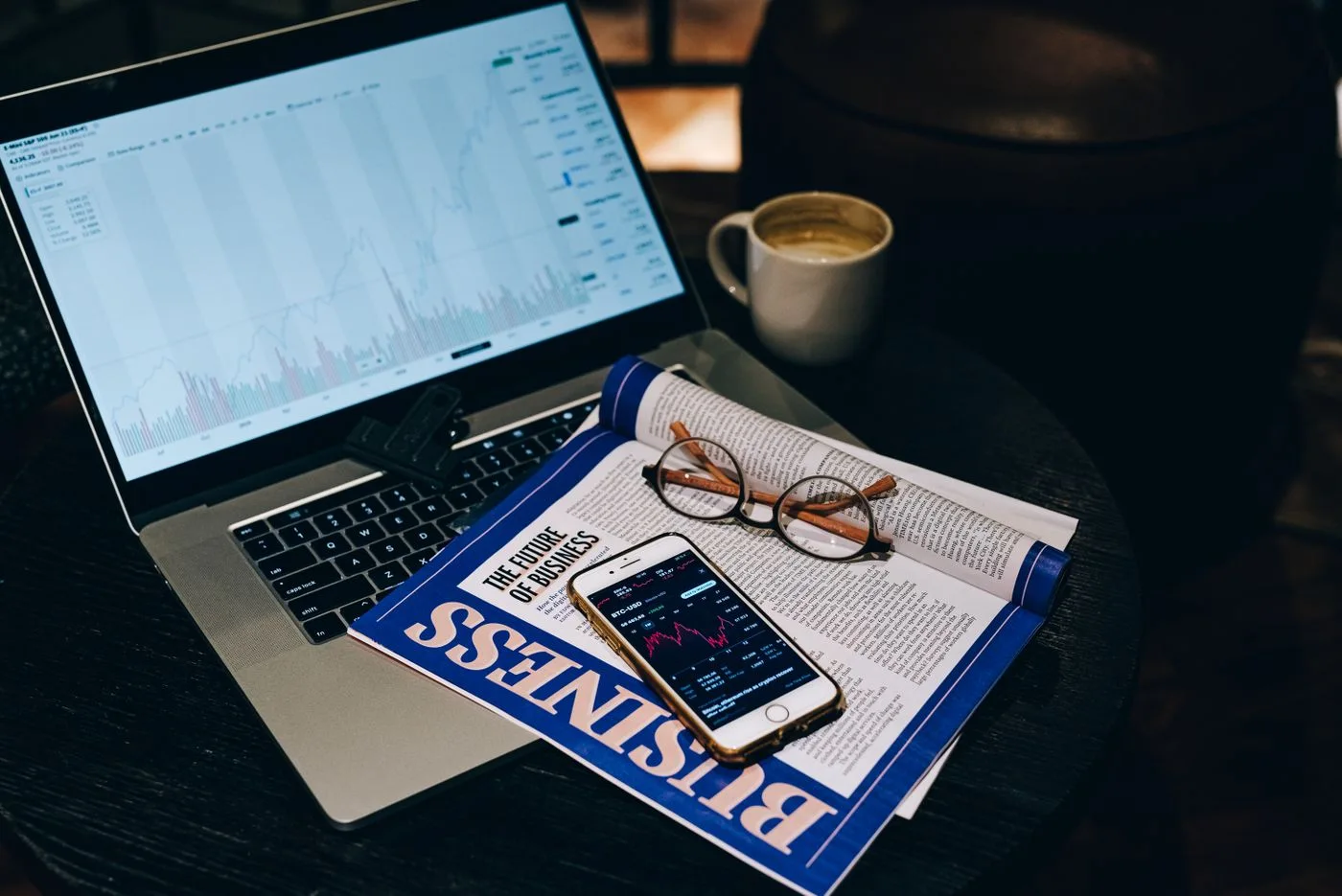 A magazine beside a laptop and smartphone