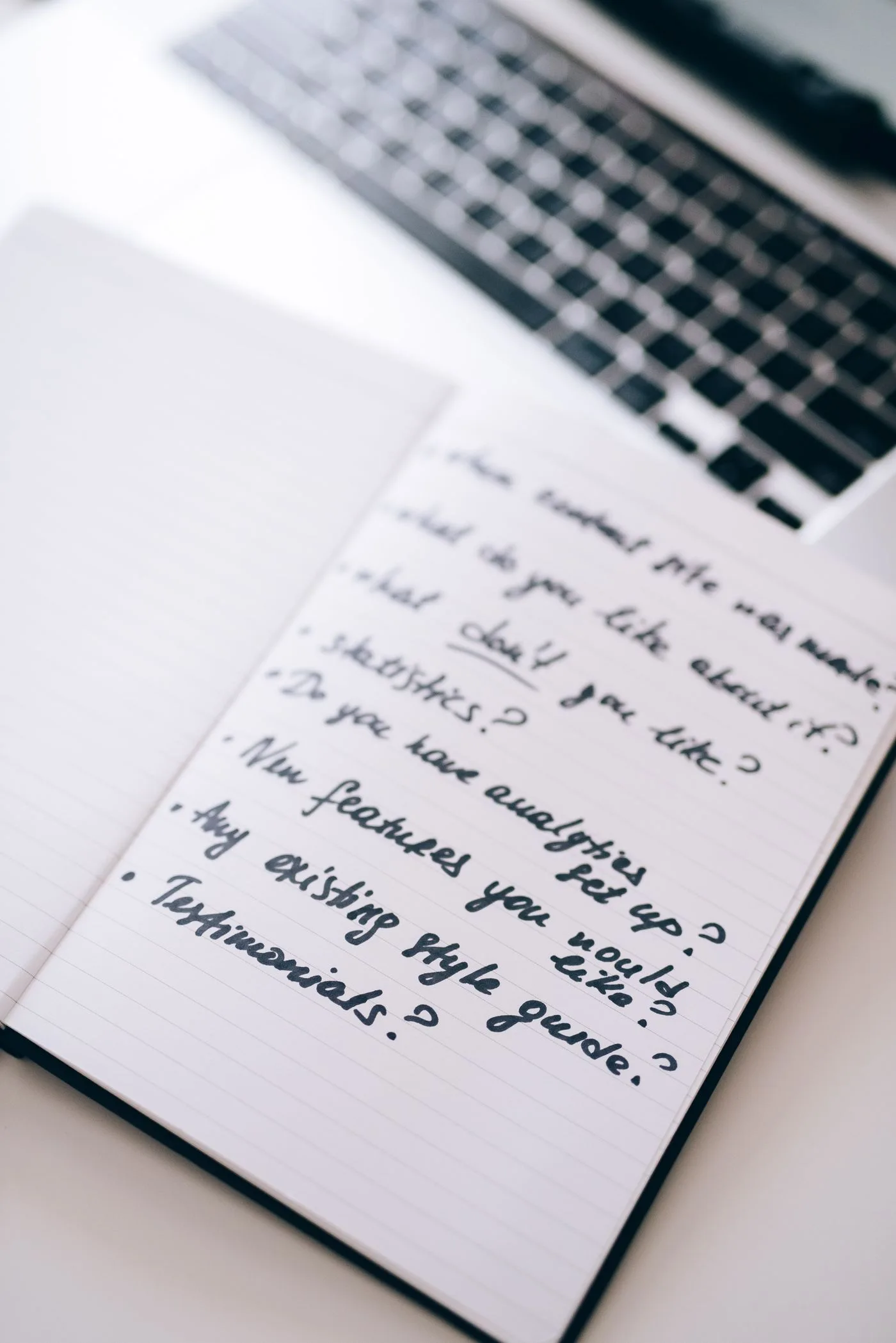 Handwritten business notes next to a laptop