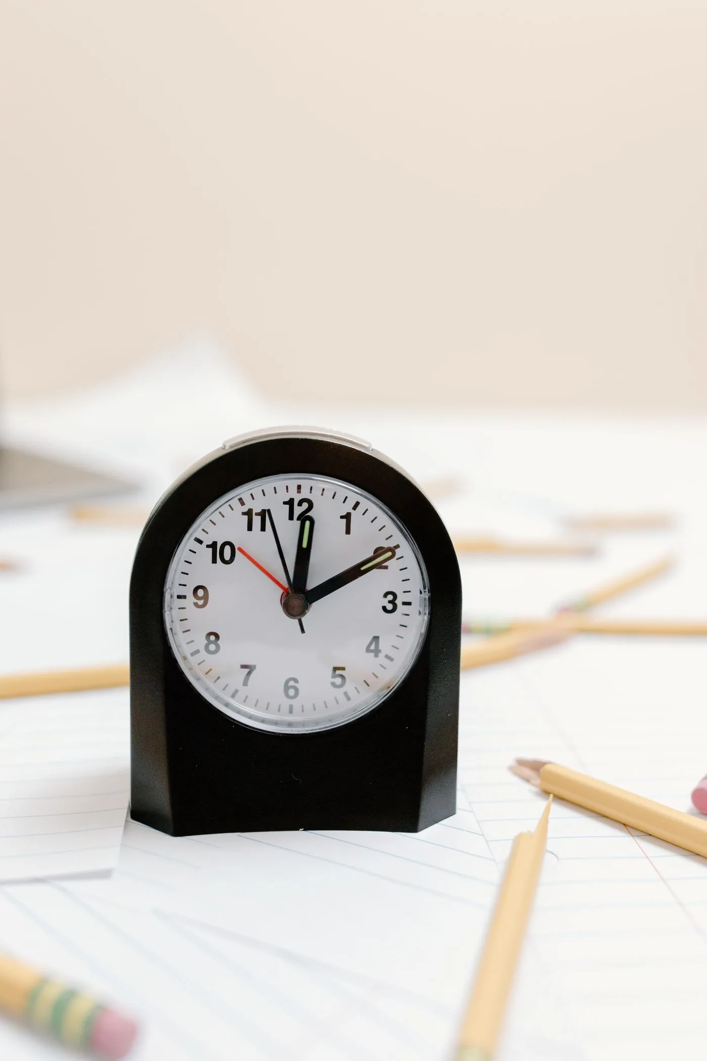 A desk clock among papers and pencils