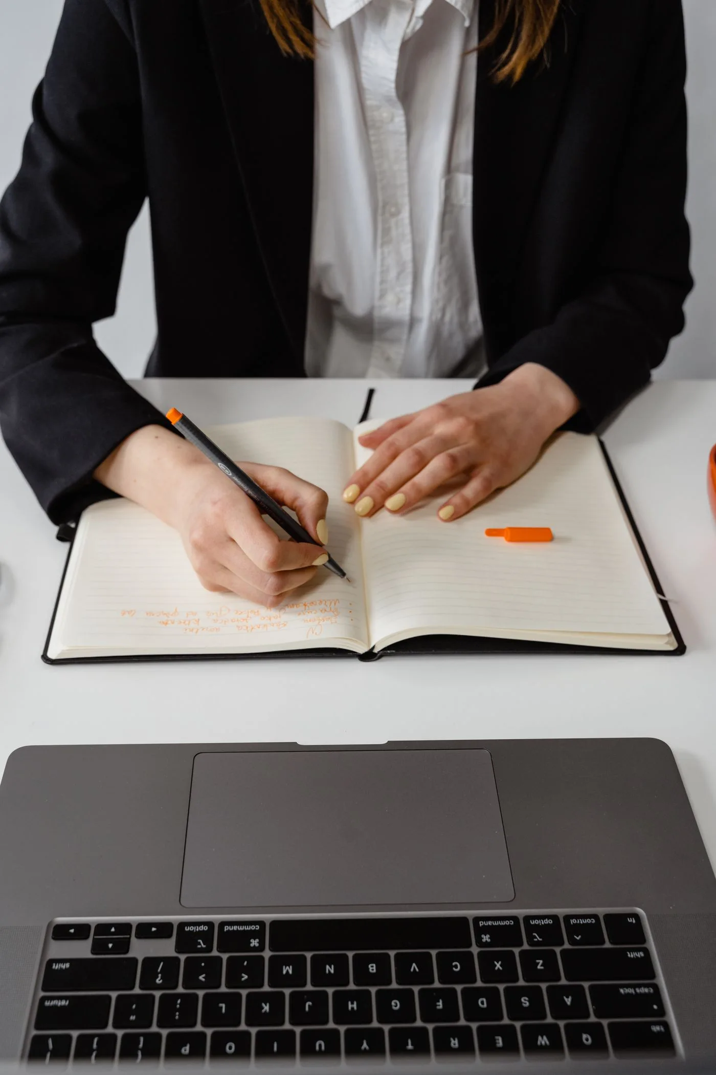 Writing notes at a laptop workspace