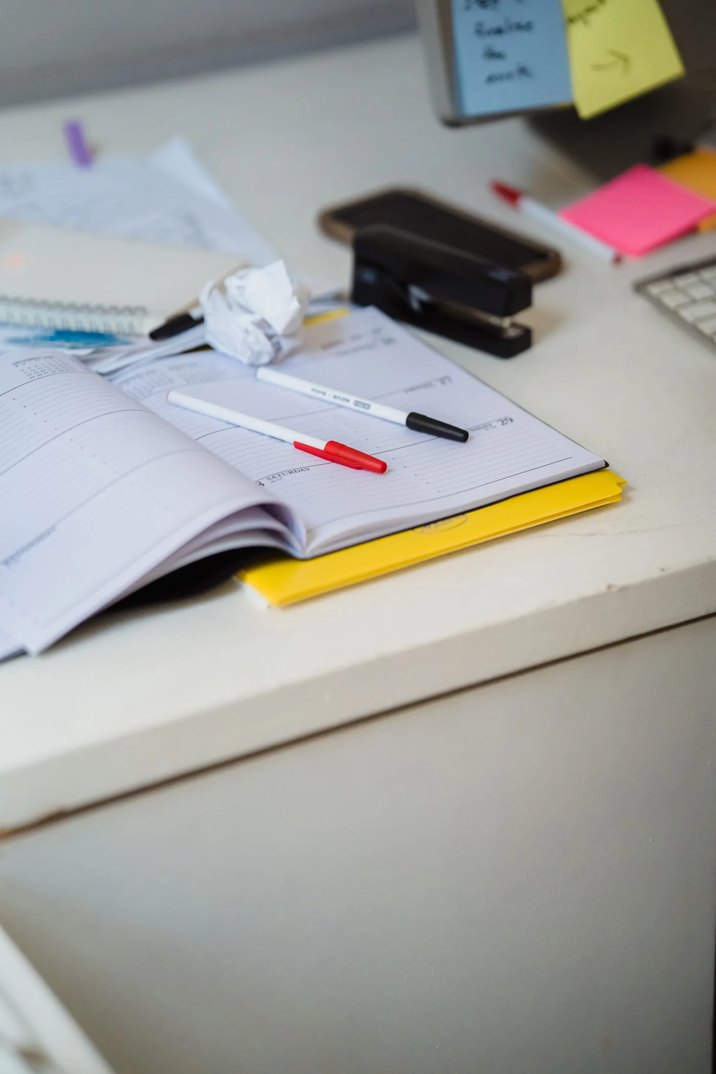 A planner and stationery on an office desk